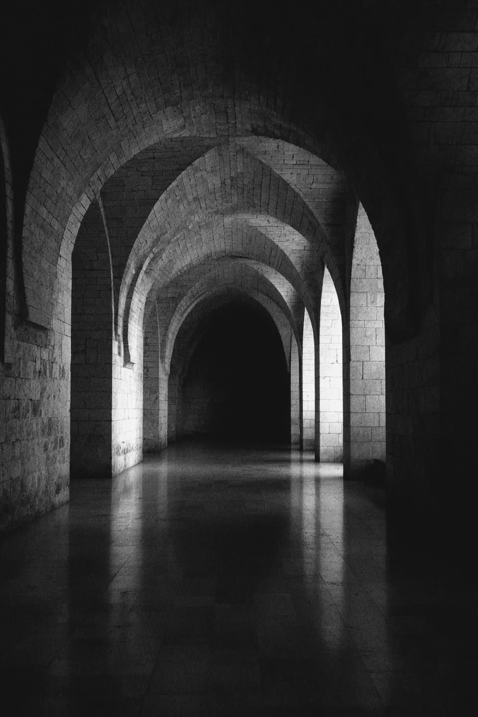 A long stone corridor of repeating arches before dawn.